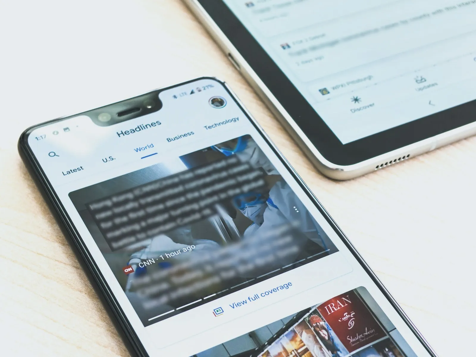 A phone open to a news headlines page beside a tablet